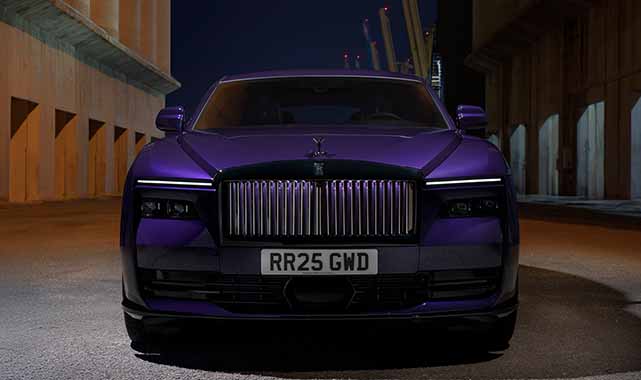 Front view of the Rolls-Royce Black Badge Spectre, featuring its illuminated grille, Spirit of Ecstasy emblem, and sleek LED headlights.