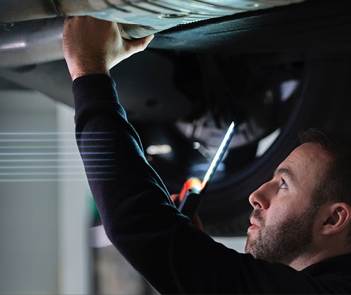 Certified mechanic working on under carriage of vehicle